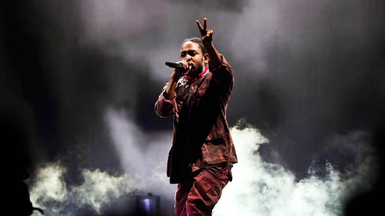 Kendrick Lamar beim Panorama Music Festival 2016 in New York. Der Musiker steht vor dunklem Hintergrund und macht mit einer Hand das Peace-Zeichen Kendrick Lamar beim Panorama Music Festival 2016 in New York. Der Musiker steht vor dunklem Hintergrund und macht mit einer Hand das Peace-Zeichen