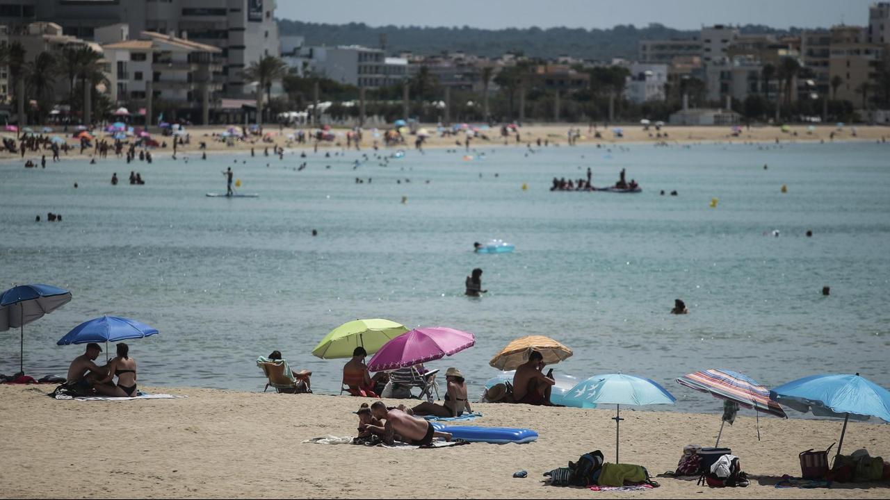 Badegäste liegen an einem Strand auf Mallorca. Badegäste liegen an einem Strand auf Mallorca.