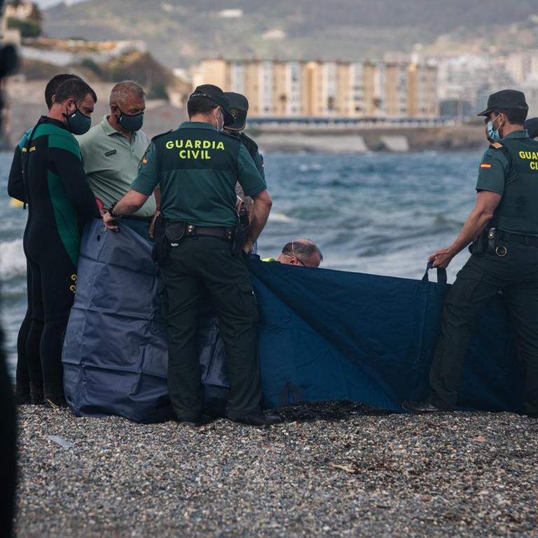 CEUTA, SPAIN - MAY 20: Spanish Guardia Civil members inspect the body of a migrant at the beach of the Spanish enclave of Ceuta on May 20, 2021. Eight thousand migrants tried to swim and walk through the Moroccan-Spanish border, thousands of them have been returned to Morocco and hundreds of minors are in a shelter. Diego Radames / Anadolu Agency