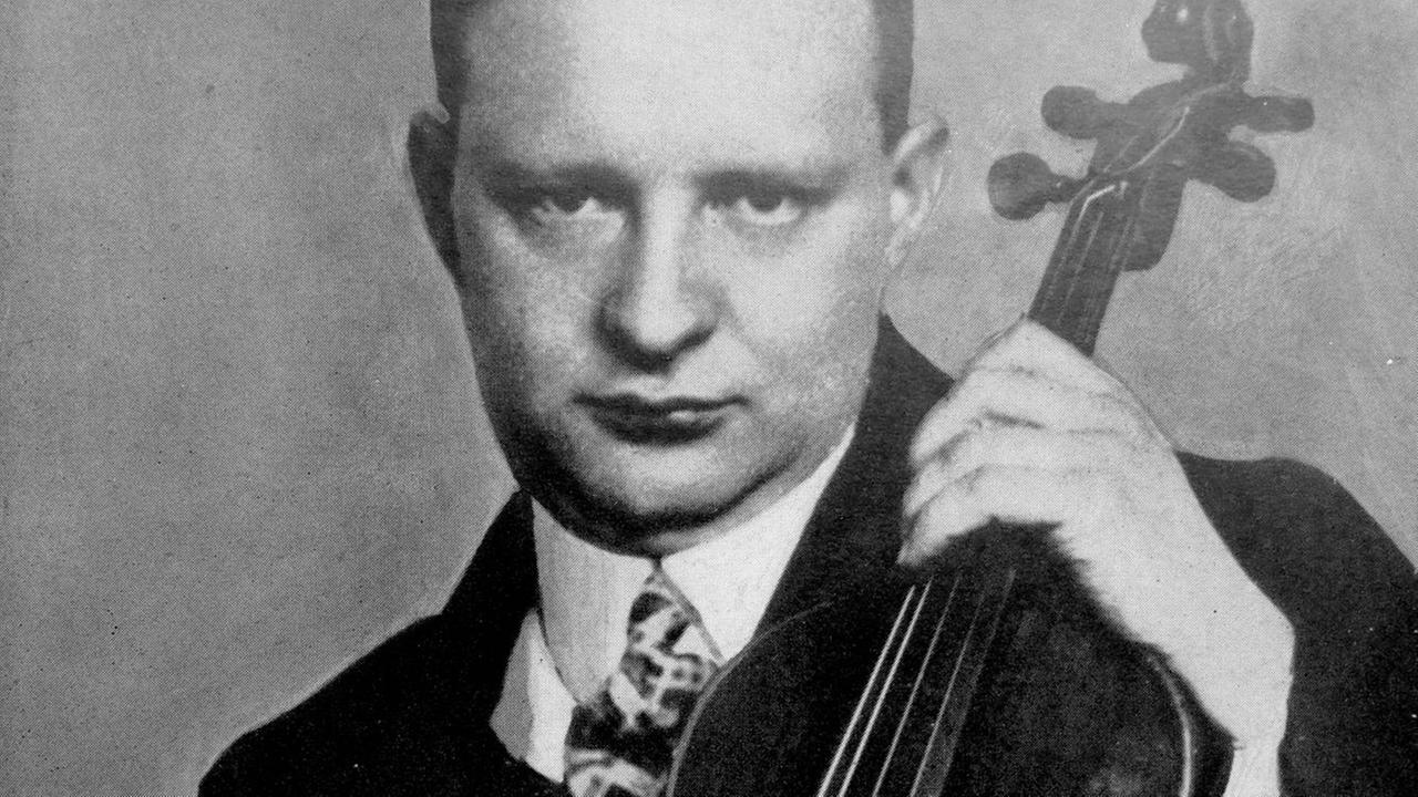 Ein Mann präsentiert auf einem Schwarz-weiß-Foto sein Streichinstrument. Ein Mann präsentiert auf einem Schwarz-weiß-Foto sein Streichinstrument.