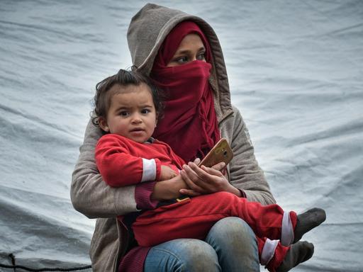 Momentaufnahme aus dem Flüchtlingslager Moria auf der Insel Lesbos am 10.03.2020. Zu sehen ist eine junge Frau, die ein kleines Kind im Arm hält.