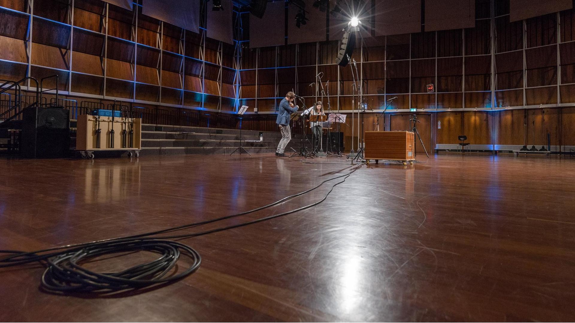 Mann mit Bratsche und Frau mit Blockflöte musizieren vor Notenständern und Mikrofonen im leeren Dlf Kammermusiksaal Mann mit Bratsche und Frau mit Blockflöte musizieren vor Notenständern und Mikrofonen im leeren Dlf Kammermusiksaal