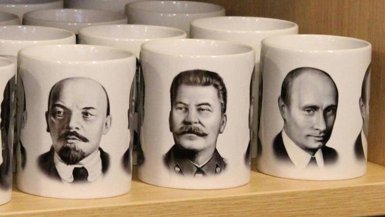 Die Gesichter Lenins, Stalins und Putins auf nebeneinanderstehenden Tassen Die Gesichter Lenins, Stalins und Putins auf nebeneinanderstehenden Tassen