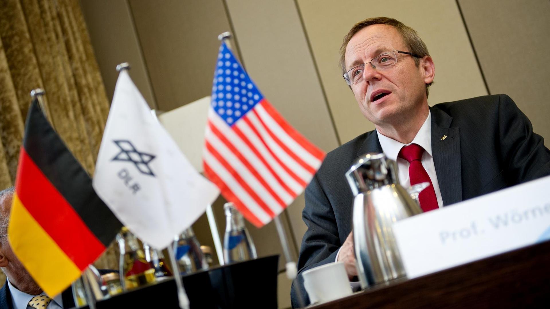 Johann-Dietrich Wörner bei einer Pressekonferenz hinter Flaggen Deutschlands, der USA und des Deutschen Zentrums für Luft- und Raumfahrt. Johann-Dietrich Wörner bei einer Pressekonferenz hinter Flaggen Deutschlands, der USA und des Deutschen Zentrums für Luft- und Raumfahrt.