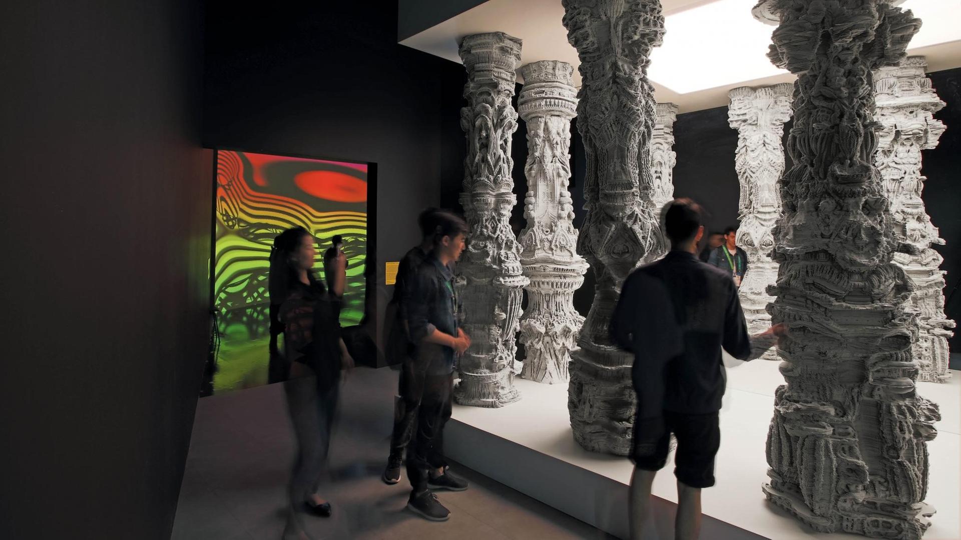 Ausstellungsbesucher stehen vor den weißen Säulen des Kunstwerkes "Astana Columns" von Michael Hansmeyer Ausstellungsbesucher stehen vor den weißen Säulen des Kunstwerkes "Astana Columns" von Michael Hansmeyer