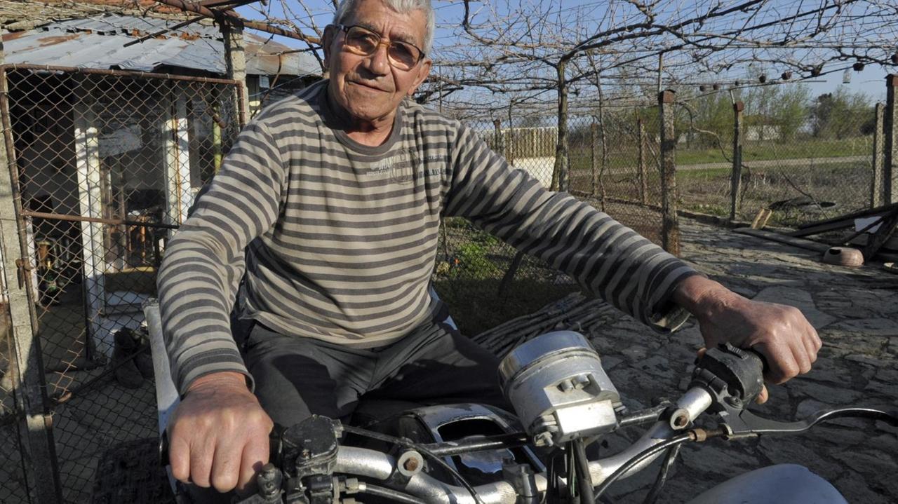 Ein älterer Mann sitzt stolz auf seinem Motorrad Ein älterer Mann sitzt stolz auf seinem Motorrad