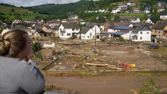 Eine Frau blickt auf die Zerstörungen in einem Ort im Kreis Ahrweiler am Tag nach dem Unwetter. Mindestens sechs Häuser wurden durch die Fluten zerstört.
