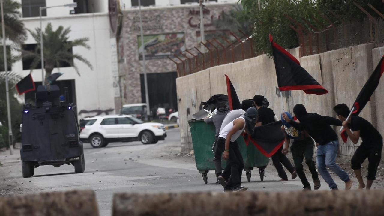 Eine Gruppe Protestierender und ein Fahrzeug der Sicherheitskräfte in Bahrain