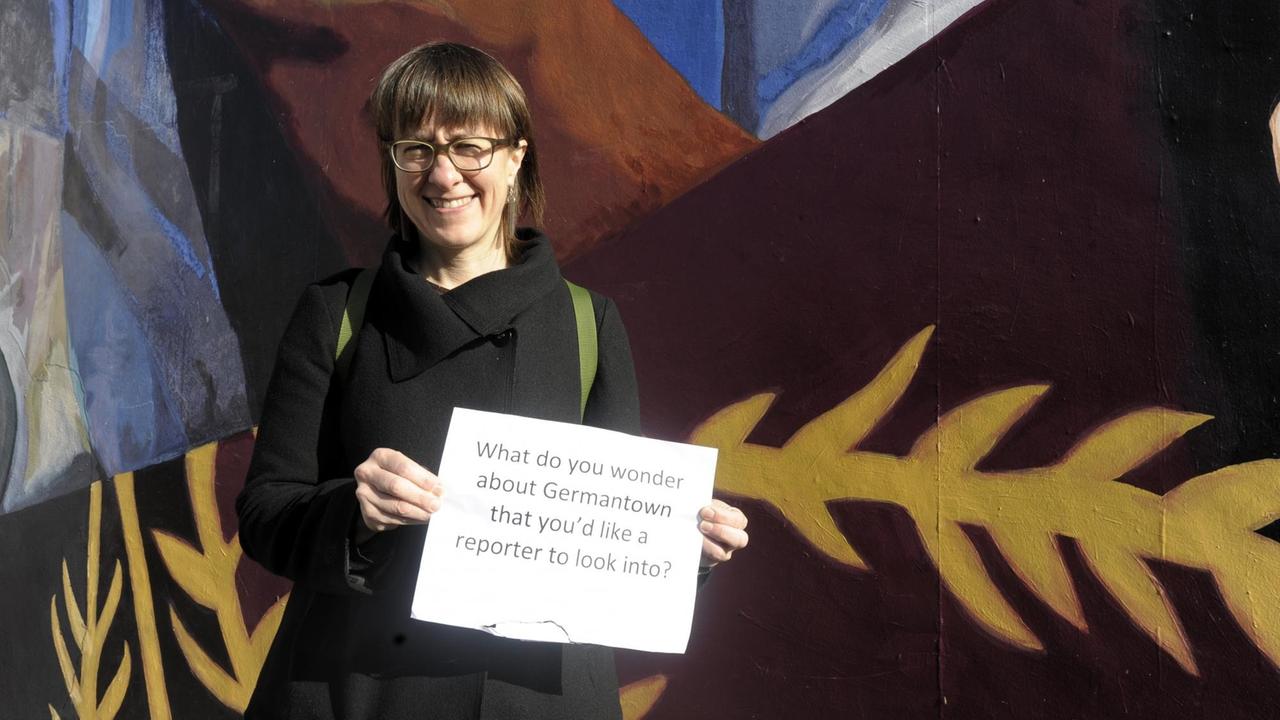 Kommunikationswissenschaftlerin Andrea Wenzel mit einem Schild, das fragt: "Welchen Fragen zu Germantown sollte ein Reporter nachgehen?"