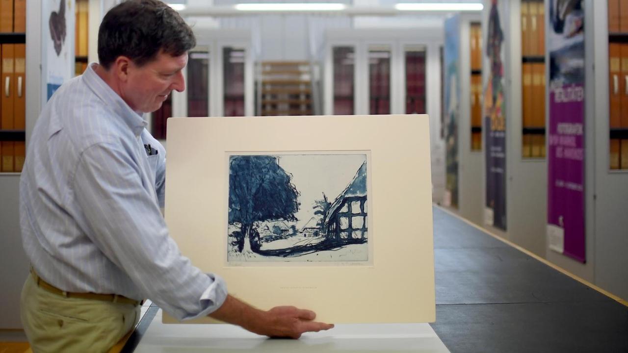 Der stellvertretende Direktor des Kupferstichkabinett Berlin, Holm Bevers, hält am 15.08.2017 in Berlin die Radierung "Fehmarnhäuser mit großem Baum" (1908) des Künstlers Ernst Ludwig Kirchner in der Hand. kaufte den blauen Probedruck einer Radierung nach der Rückgabe an die Erben des jüdischen Sammlers Eugen Moritz Buchtal nun zurück. Der stellvertretende Direktor des Kupferstichkabinett Berlin, Holm Bevers, hält am 15.08.2017 in Berlin die Radierung "Fehmarnhäuser mit großem Baum" (1908) des Künstlers Ernst Ludwig Kirchner in der Hand. kaufte den blauen Probedruck einer Radierung nach der Rückgabe an die Erben des jüdischen Sammlers Eugen Moritz Buchtal nun zurück.