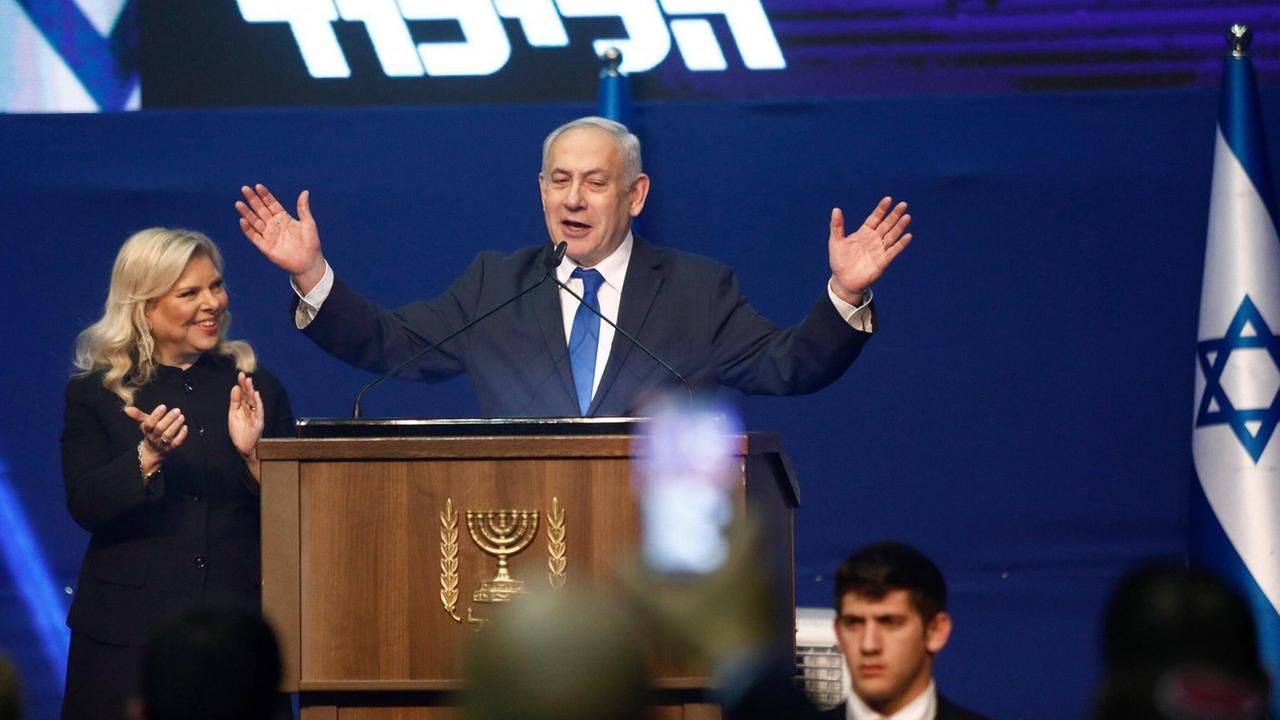 Israels Premierminister Benjamin Netanjahu am Rednerpult. Links: seine Frau Sara