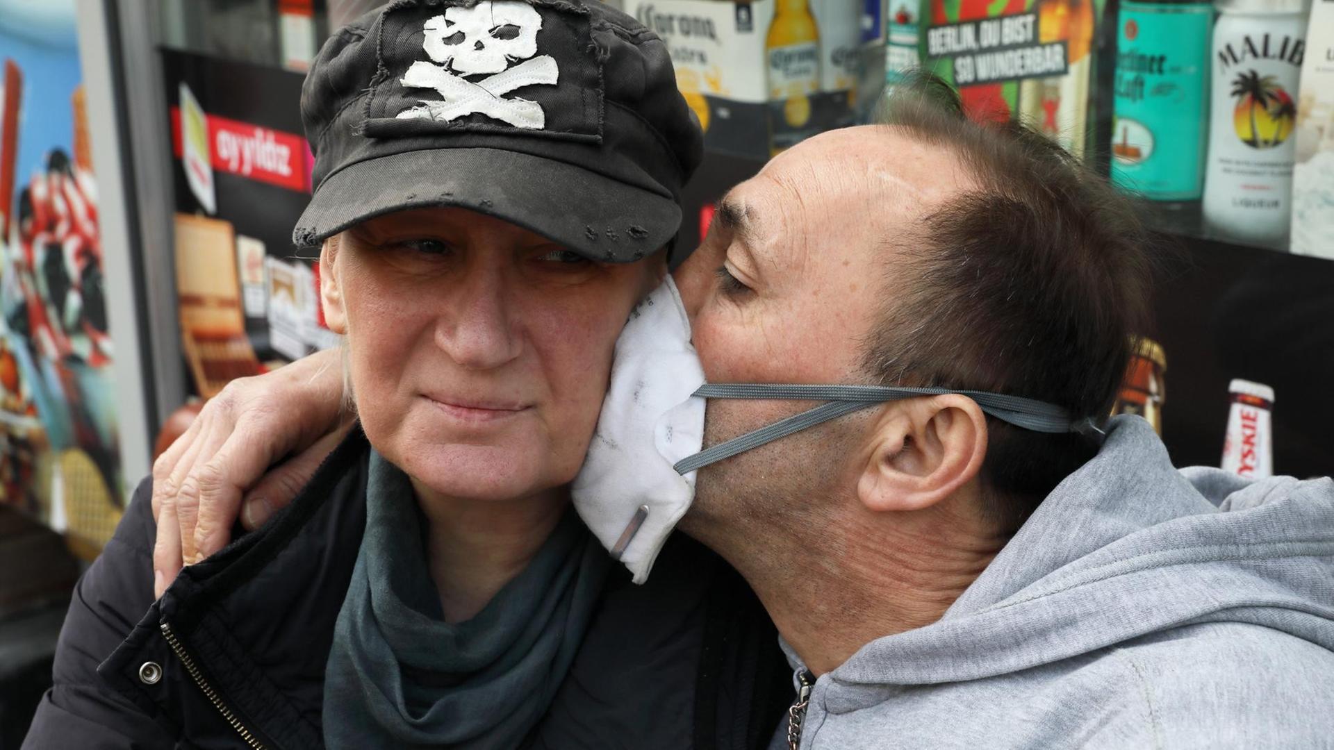 Ein Mann küsst eine Frau durch einen Mundschutz. Ein Mann küsst eine Frau durch einen Mundschutz.
