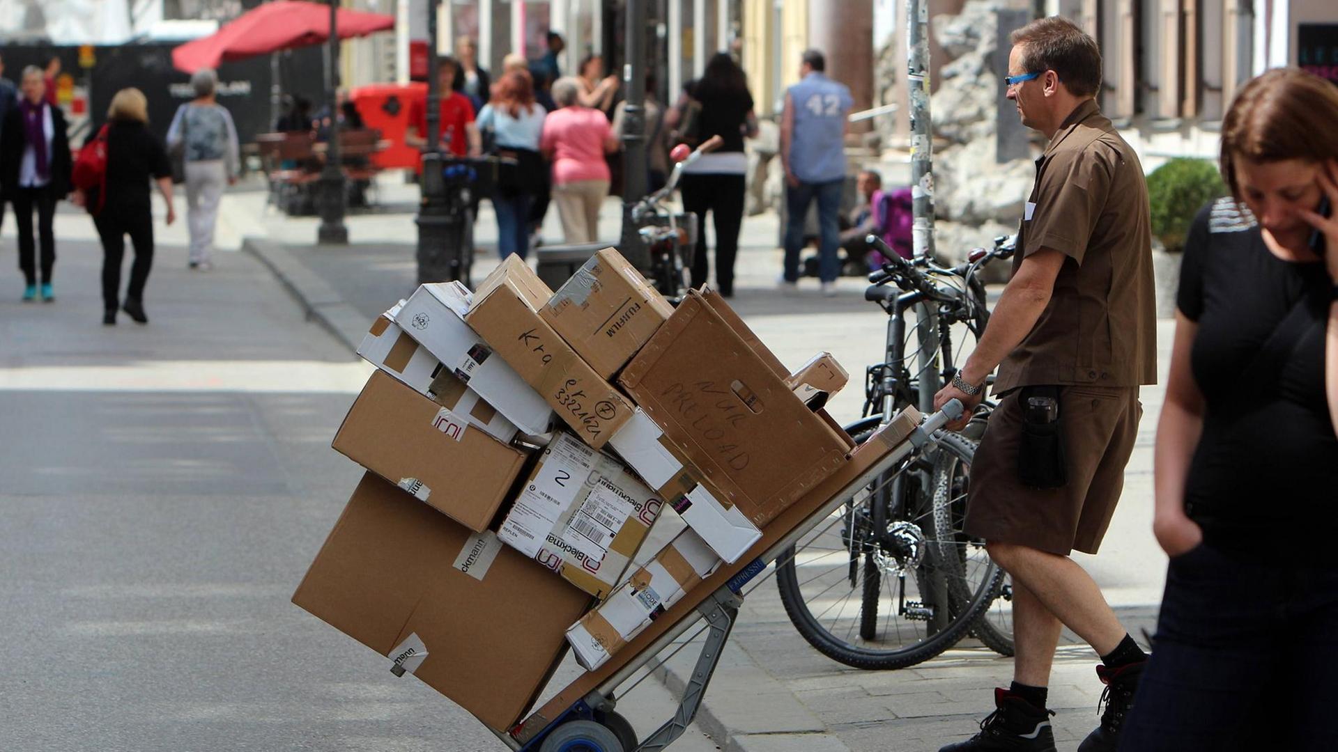 Paketzusteller liefert Pakete auf einem vollbeladenen Karren aus. Paketzusteller liefert Pakete auf einem vollbeladenen Karren aus.