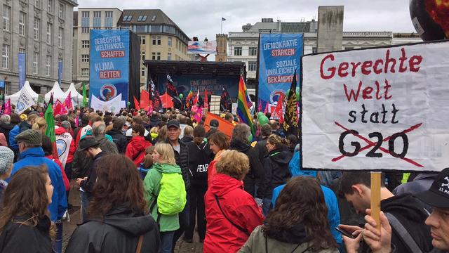 Teilnehmer der Großdemo gegen die Politik der G20-Staaten in Hamburg halten Plakate und Transparente hoch