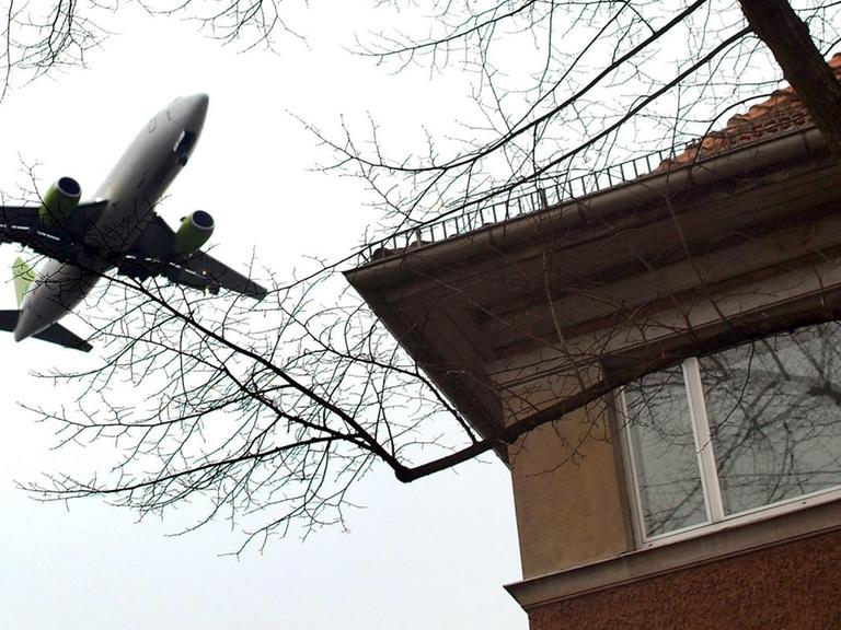 Ein Flugzeug fliegt dicht über ein Wohnhaus in Berlin-Tegel.