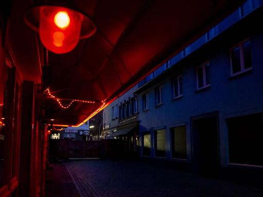 Blick in die leere Herbertstraße bei Nacht. Nur eine rote Laterne leuchtet in der dunklen Straße.