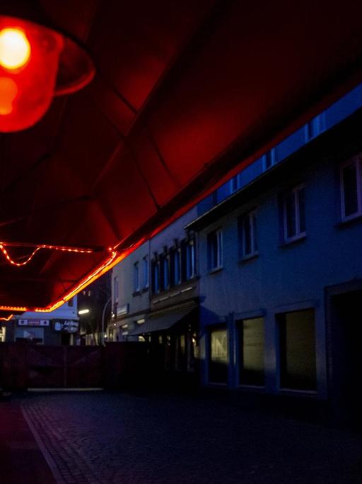 Blick in die leere Herbertstraße bei Nacht. Nur eine rote Laterne leuchtet in der dunklen Straße.