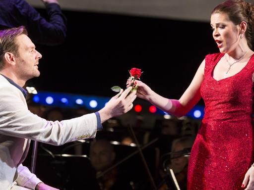 Sänger Daniel Jenz und Sängerin Sieglinde Feldhofer auf der Bühne in einer Szene der Operette "Clo-Clo" von Franz Lehár. Jenz gibt Feldhofer eine rote Rose.