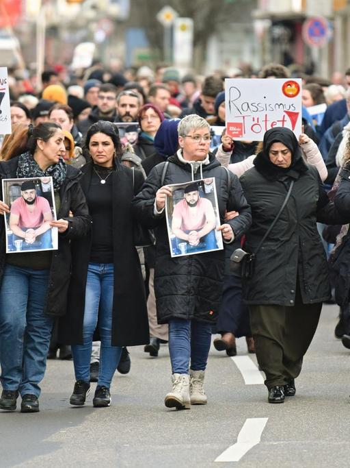 Zahlreiche Menschen gehen bei einem Trauermarsch vom Tatort Heumarkt zum Tatort Kurt-Schumacher-Platz und halten dabei Fotos der Opfer in den Händen.