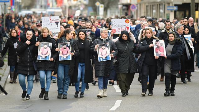 Zahlreiche Menschen gehen bei einem Trauermarsch vom Tatort Heumarkt zum Tatort Kurt-Schumacher-Platz und halten dabei Fotos der Opfer in den Händen.