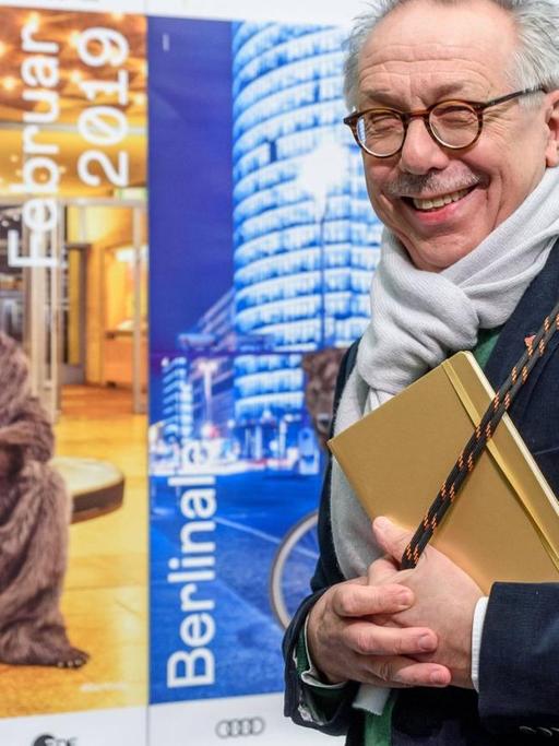 Dieter Kosslick verlässt das Podium der Pressekonferenz und blickt freundlich in die Kamera, während er eine graue Berlinaletasche schultert.