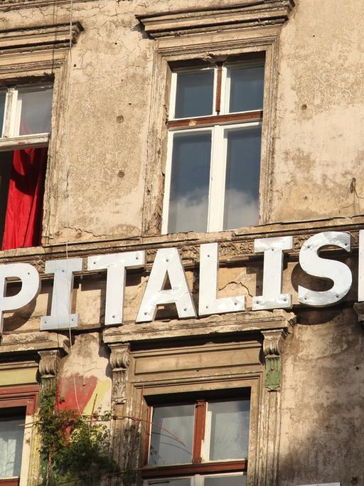 "Kapitalismus" steht auf einer Wand an einem besetzten Haus in einer Straße in Berlin im Stadtteil Prenzlauer Berg , aufgenommen am 11. August 2012.