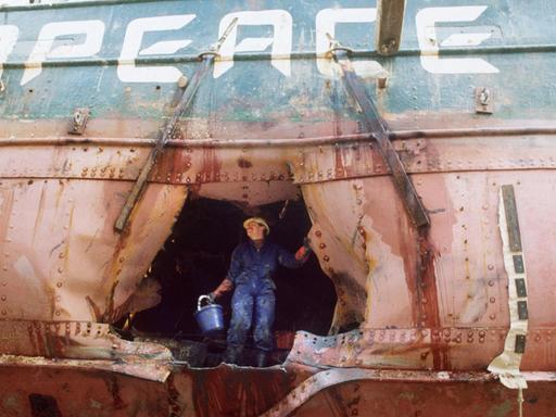 Ein Arbeiter begutachtet das Loch im Rumpf des Greenpeace-Schiffes "Rainbow Warrior", auf dem Rump ist das Wort "Peace" zu lesen.