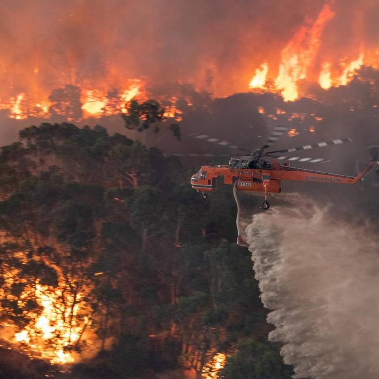 Blick auf einen  Helikopter, der Waldbrände aus der Luft löscht