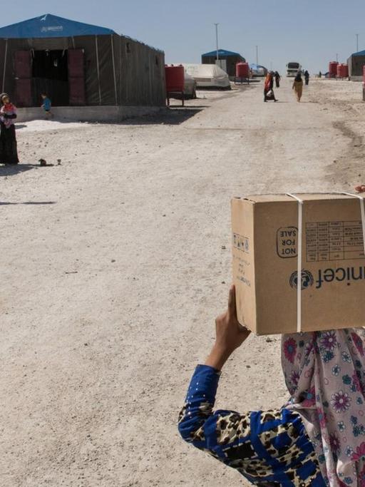 Eine junge Frau mit einem Unicef-Karton an einer Straße in der Nähe Rakkas