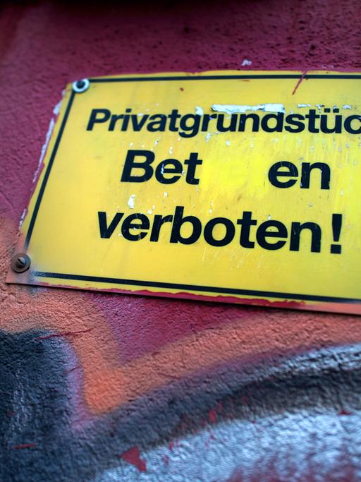 "Privatgrundstück - Beten verboten" steht auf einem Schild an einer Garagenwand in Dresden (Sachsen).