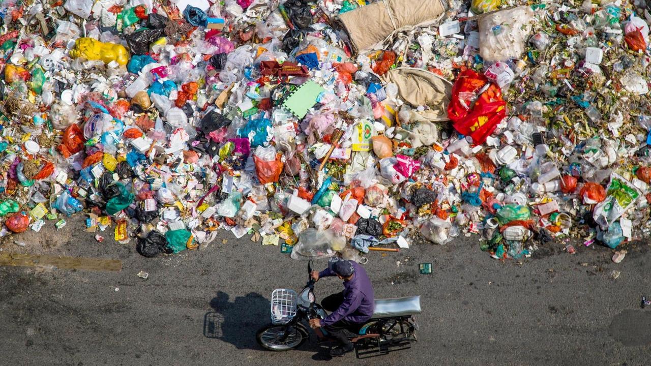 Ein chinesischer Radfahrer fährt an einem Haufen Abfall vorbei, der am 20. November 2014 auf einer Straße in Shiyan-Stadt in der Südchinesische Guangdong-Provinz, liegt.