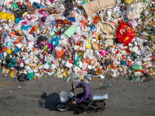 Ein chinesischer Radfahrer fährt an einem Haufen Abfall vorbei, der am 20. November 2014 auf einer Straße in Shiyan-Stadt in der Südchinesische Guangdong-Provinz, liegt.