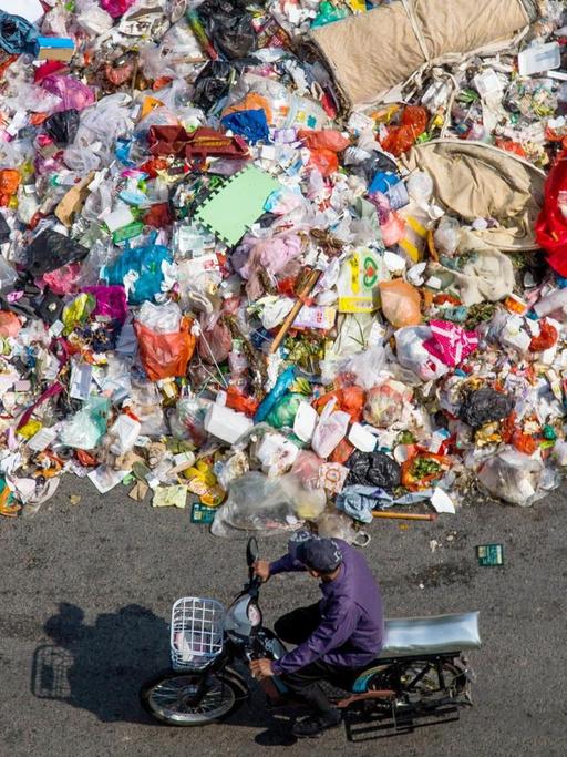 Ein chinesischer Radfahrer fährt an einem Haufen Abfall vorbei, der am 20. November 2014 auf einer Straße in Shiyan-Stadt in der Südchinesische Guangdong-Provinz, liegt.