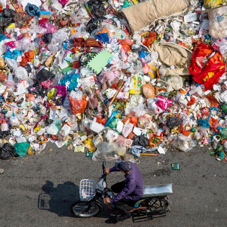 Ein chinesischer Radfahrer fährt an einem Haufen Abfall vorbei, der am 20. November 2014 auf einer Straße in Shiyan-Stadt in der Südchinesische Guangdong-Provinz, liegt.