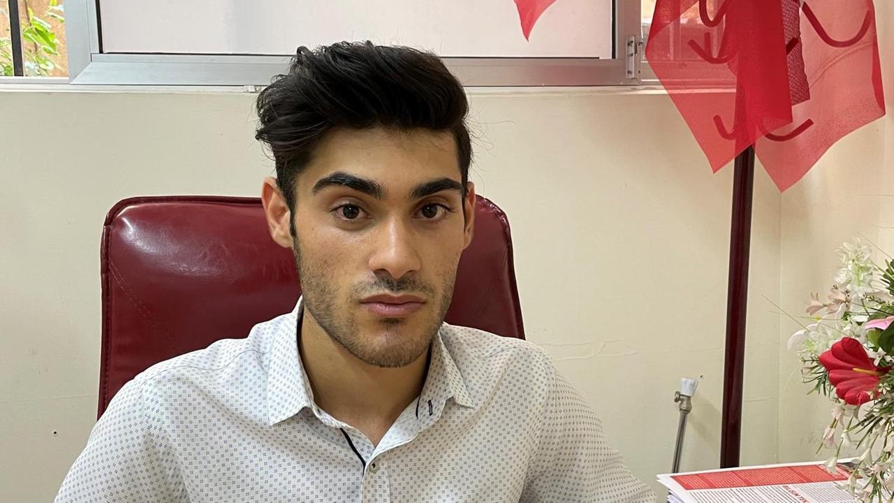 Ein junger Mann mit Dreitagebart und dunklem Wuschelkopf sitzt im weißen Hemd auf einem Bürostuhl. Ein junger Mann mit Dreitagebart und dunklem Wuschelkopf sitzt im weißen Hemd auf einem Bürostuhl.