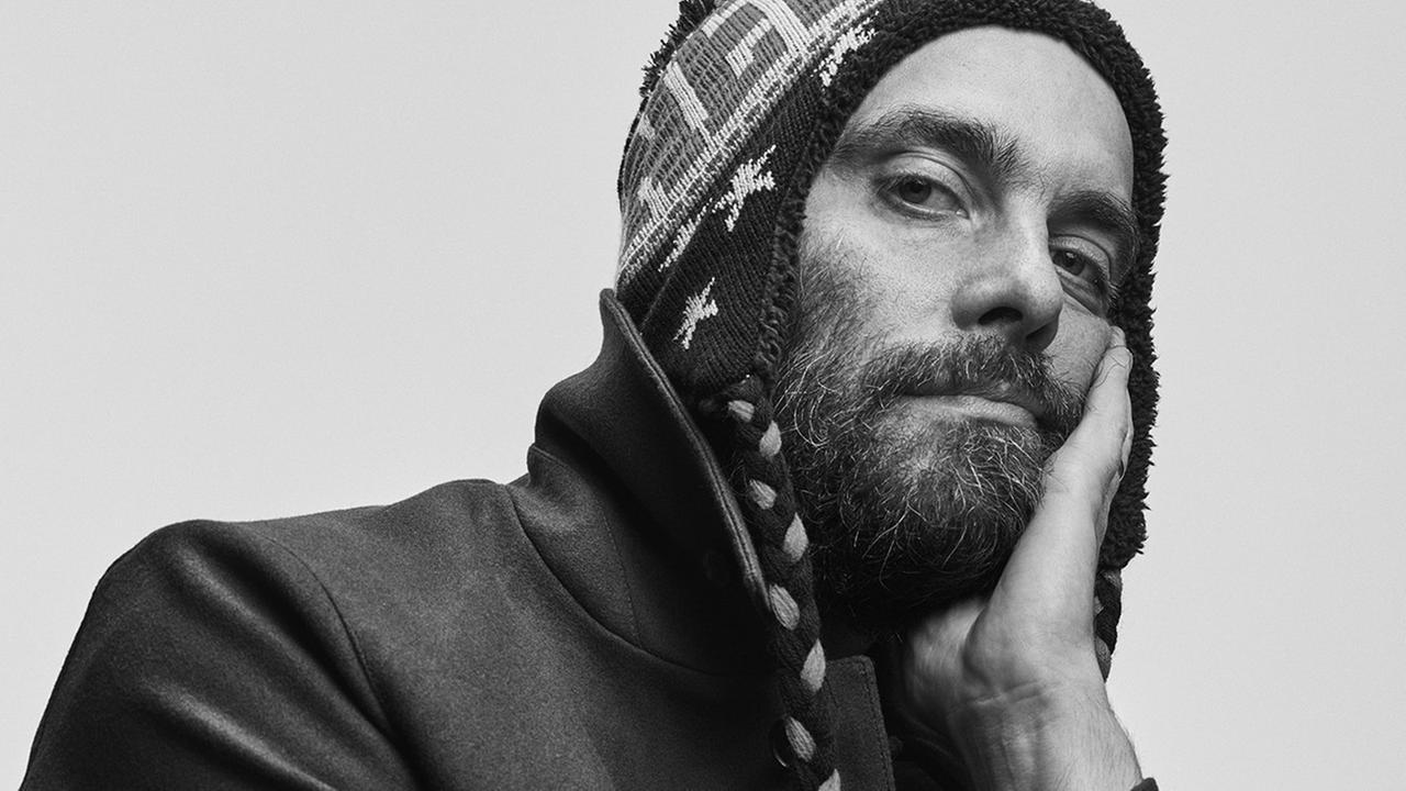Ein Schwarz-Weiß-Porträt-Foto des Künstlers Henrik Eiben. Er trägt eine Strickmütze und blickt in die Kamera. Ein Schwarz-Weiß-Porträt-Foto des Künstlers Henrik Eiben. Er trägt eine Strickmütze und blickt in die Kamera.