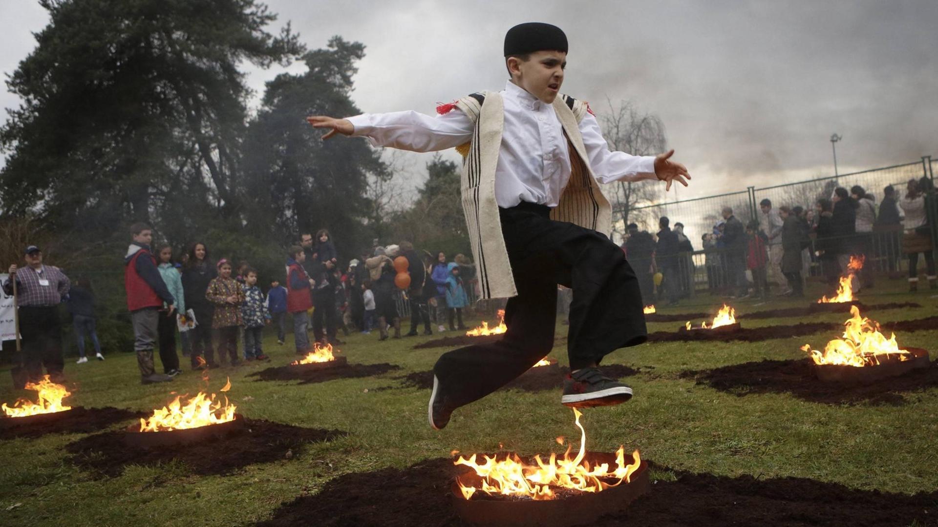 Ein Junge springt bei den Feierlichkeiten zum Persischen Neujahr über ein Lagerfeuer. Das Bild ist bei Feierlichkeiten der Iranischen Community in Vancouver, Kanada aufgenommen. Ein Junge springt bei den Feierlichkeiten zum Persischen Neujahr über ein Lagerfeuer. Das Bild ist bei Feierlichkeiten der Iranischen Community in Vancouver, Kanada aufgenommen.
