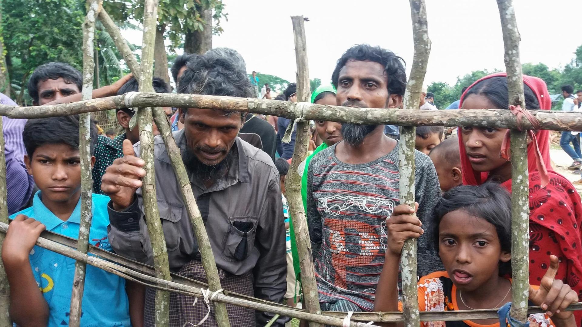 Rohingya-Flüchtlinge stehen hinter einem Holzzaun. Rohingya-Flüchtlinge stehen hinter einem Holzzaun.
