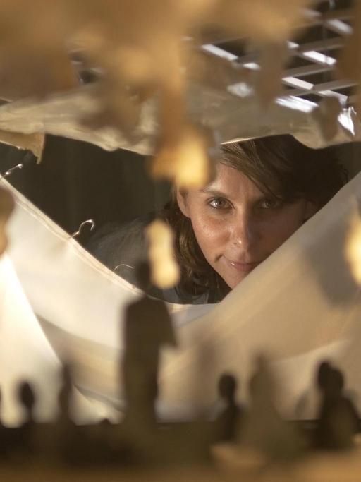 Die Komponistin Ashley Fure blickt durch den Spalt einer Skulptur