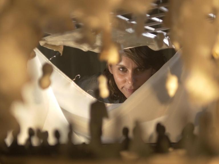 Die Komponistin Ashley Fure blickt durch den Spalt einer Skulptur