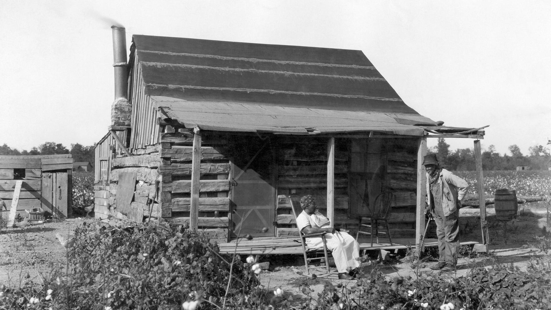 Sklaven im Jahre 1895 vor ihrer Hütte auf einem Baumwollfeld. Sklaven im Jahre 1895 vor ihrer Hütte auf einem Baumwollfeld.