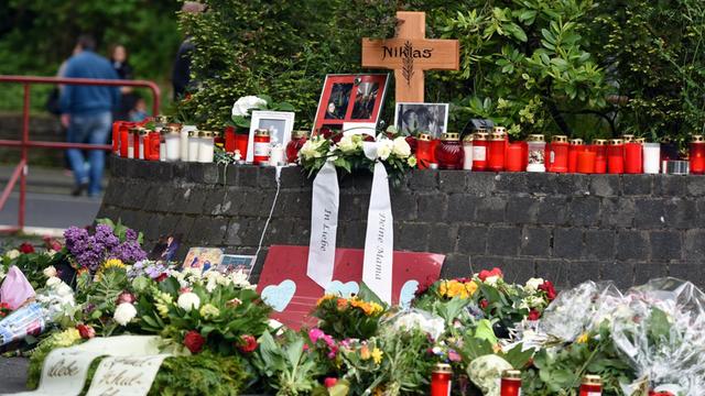 Blumen und Kerzen stehen in Bonn (Nordrhein-Westfalen) vor und neben dem Kreuz an der Stelle, an der der nun verstobene Niklas P. (17) von bisher Unbekannten zusammengeschlagen wurde.