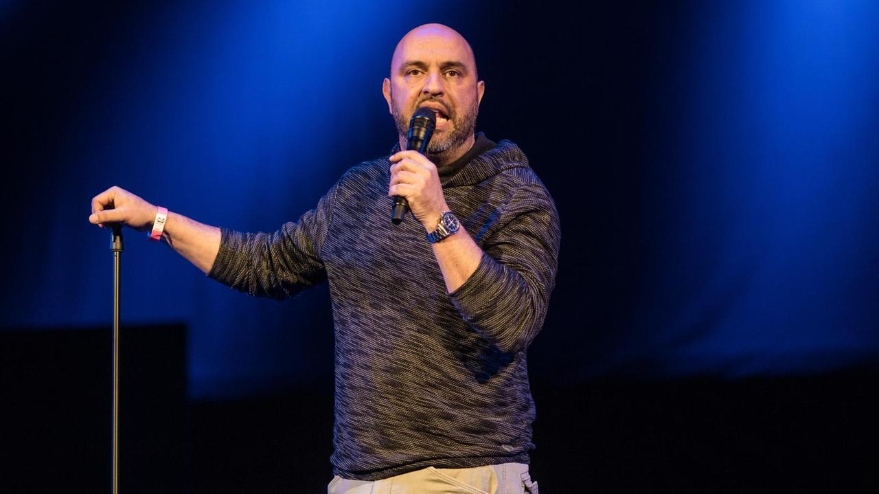 Der Kabarettist Serdar Somuncu steht auf einer dunklen Bühne Der Kabarettist Serdar Somuncu steht auf einer dunklen Bühne