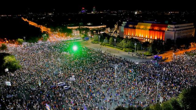 Tausende Menschen stehen auf einem Platz. Von oben ist grünes Licht zu sehen. Es sind Laserpointer der Demonstranten.