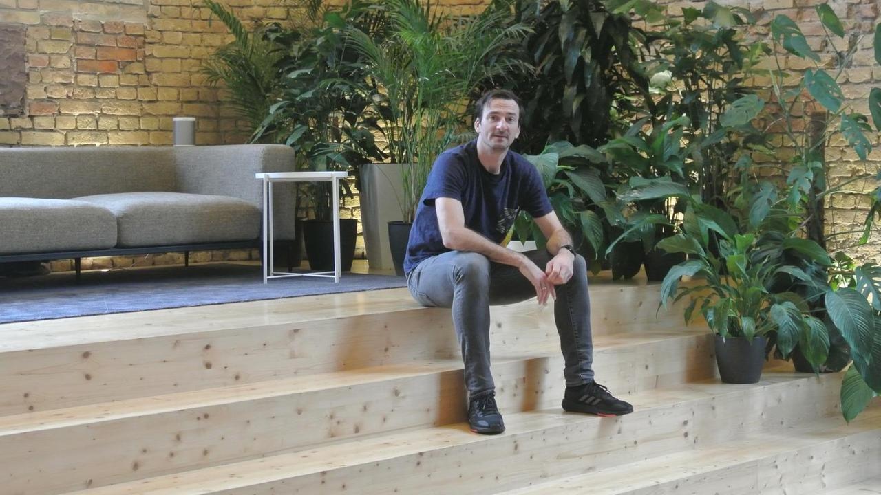 Ein Mann sitzt in einem großen Raum auf einer Holztreppe. Ein Mann sitzt in einem großen Raum auf einer Holztreppe.