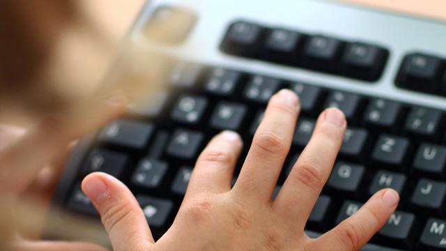 Eine Hand schreibt auf einer Tastatur. 