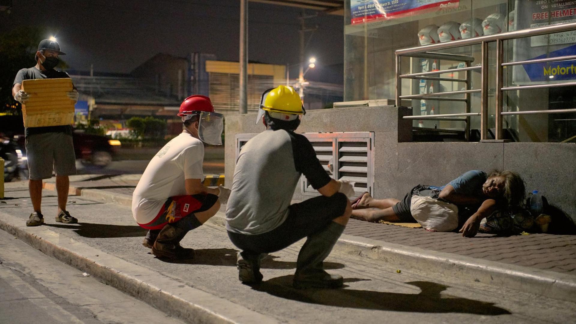 An Obdachlose werden auf einer Straße in Manila Essen und Maske verteilt. An Obdachlose werden auf einer Straße in Manila Essen und Maske verteilt.