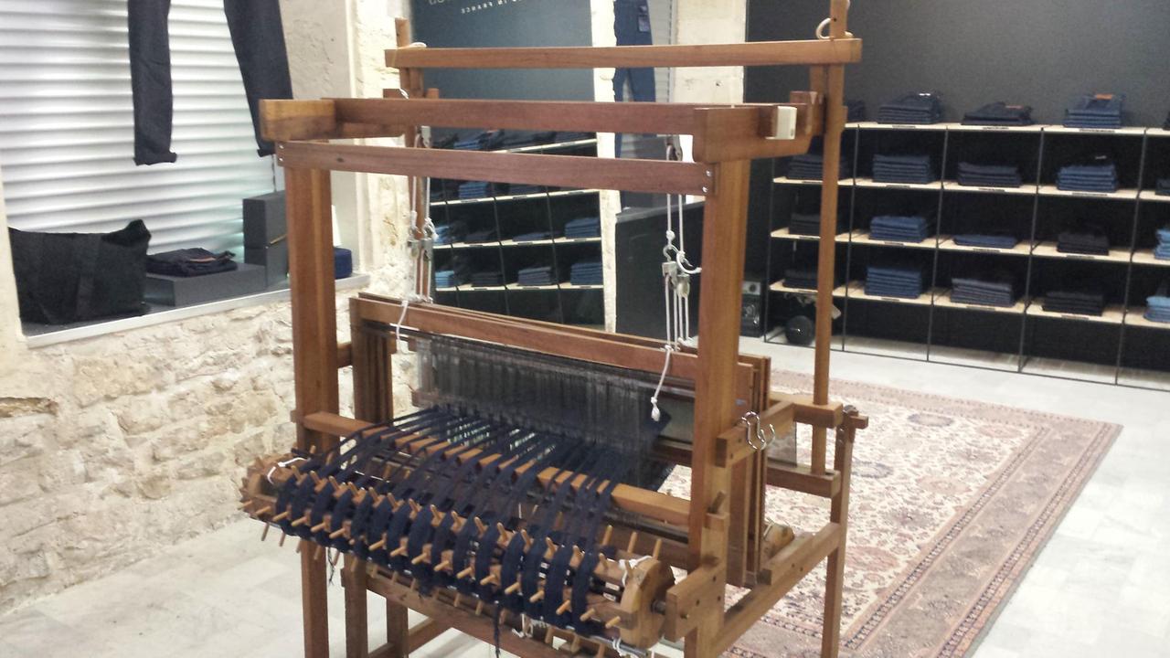 In der Boutique der Jeans-Produzenten von "Ateliers de Nîmes" steht auch ein alter funktionsfähiger Webstuhl als Dekoration. Dahinter Regale mit Jeans. In der Boutique der Jeans-Produzenten von "Ateliers de Nîmes" steht auch ein alter funktionsfähiger Webstuhl als Dekoration. Dahinter Regale mit Jeans.