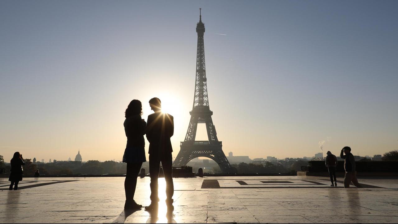 Menschen schauen sich vom Trocadero in Paris aus den Sonnenaufgang am Eiffelturm an. Menschen schauen sich vom Trocadero in Paris aus den Sonnenaufgang am Eiffelturm an.