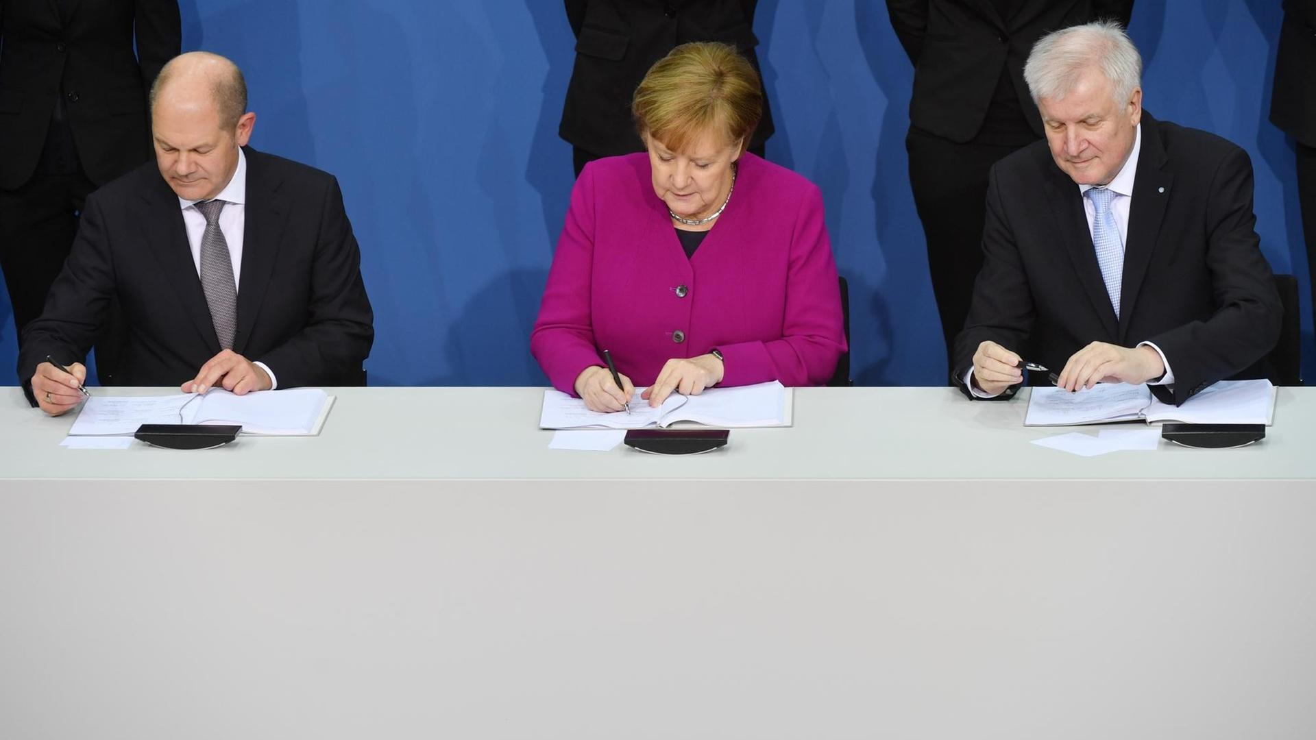 Bundeskanzlerin Angela Merkel (CDU), der CSU-Vorsitzende Horst Seehofer (r) und der kommissarische SPD-Vorsitzende Olaf Scholz unterzeichnen im Paul-Löbe-Haus den Koalitionsvertrag. Bundeskanzlerin Angela Merkel (CDU), der CSU-Vorsitzende Horst Seehofer (r) und der kommissarische SPD-Vorsitzende Olaf Scholz unterzeichnen im Paul-Löbe-Haus den Koalitionsvertrag.